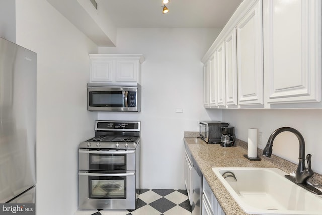 kitchen with light countertops, a sink, white cabinetry, and appliances with stainless steel finishes