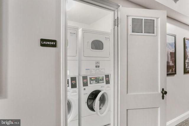 washroom with stacked washer and dryer, baseboards, and laundry area
