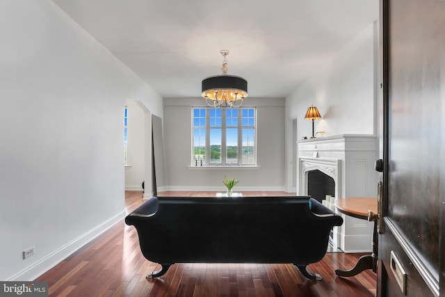 living room featuring a fireplace, wood finished floors, baseboards, and a notable chandelier