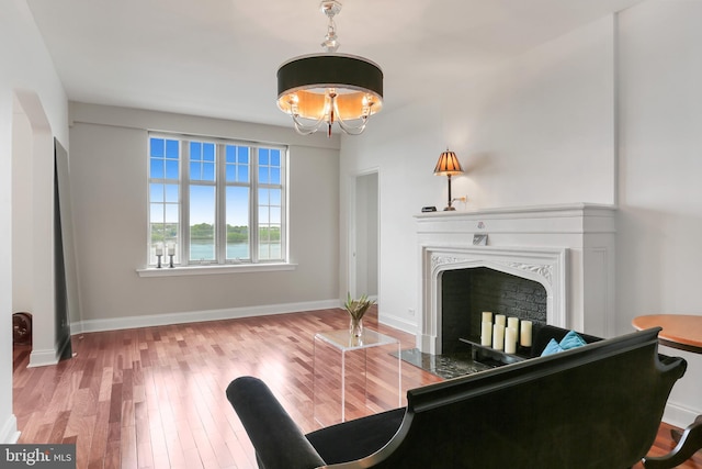 living area with baseboards, wood finished floors, a fireplace, and a notable chandelier