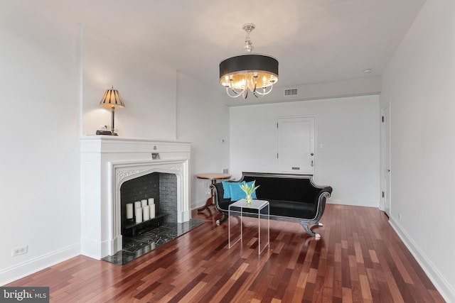sitting room with a fireplace with flush hearth, baseboards, visible vents, a chandelier, and wood finished floors