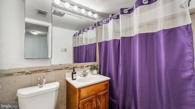 3801 Swann Rd Unit 101, Suitland, MD 20746 - bathroom with toilet, vanity, tile walls, a wainscoted wall, and a shower with curtain