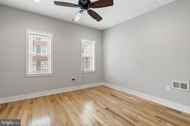 spare room with visible vents, light wood finished floors, baseboards, and a ceiling fan