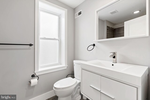 bathroom with baseboards, visible vents, toilet, and vanity