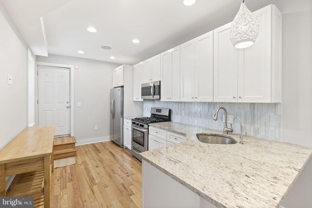 kitchen featuring recessed lighting, a sink, light wood-type flooring, appliances with stainless steel finishes, and white cabinetry
