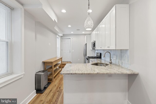 kitchen featuring a sink, stainless steel appliances, white cabinetry, light stone countertops, and recessed lighting
