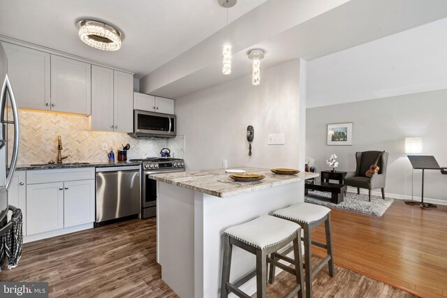 18 Canterbury Sq Unit 302, Alexandria, VA 22304 - kitchen featuring dark wood-style flooring, appliances with stainless steel finishes, a sink, a breakfast bar area, and tasteful backsplash