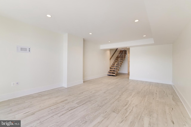 finished basement with light wood-type flooring, recessed lighting, stairs, and baseboards