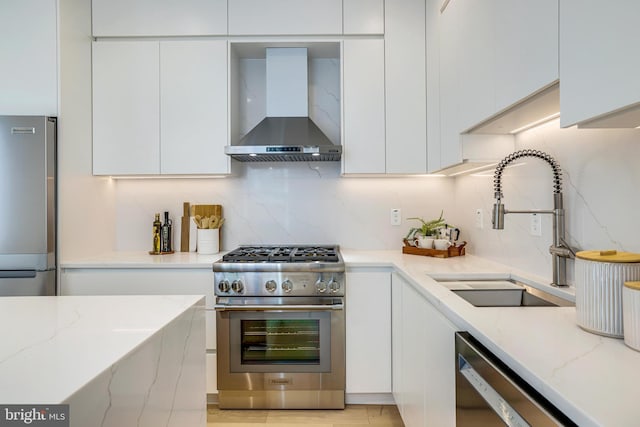 kitchen featuring modern cabinets, wall chimney exhaust hood, appliances with stainless steel finishes, and a sink