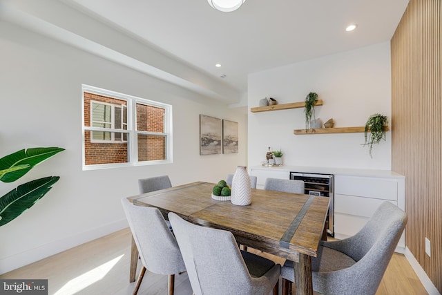 dining space with baseboards, recessed lighting, light wood-style floors, a bar, and beverage cooler