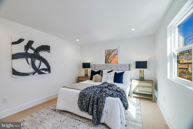 bedroom with recessed lighting, wood finished floors, and multiple windows