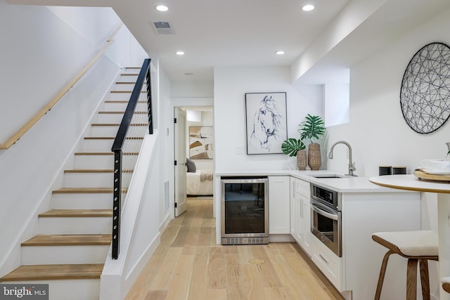 bar featuring recessed lighting, oven, wine cooler, visible vents, and a sink