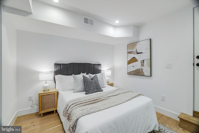 bedroom with baseboards, wood finished floors, visible vents, and recessed lighting