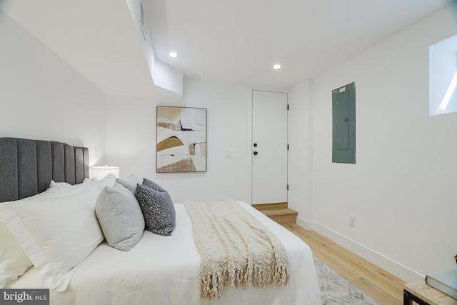 bedroom featuring baseboards, light wood finished floors, electric panel, and recessed lighting