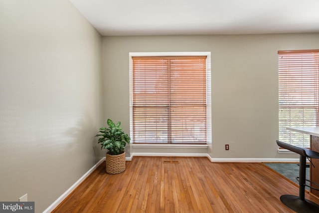 interior space with baseboards, wood-type flooring, and visible vents