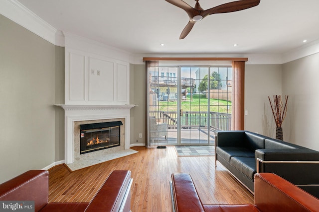 living room featuring a ceiling fan, crown molding, a fireplace, wood finished floors, and recessed lighting