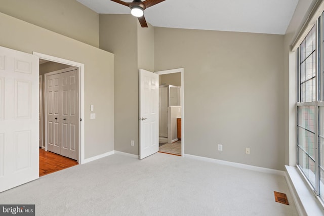 unfurnished bedroom with baseboards, carpet flooring, ensuite bath, and multiple windows