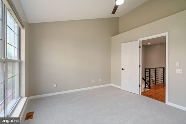 carpeted empty room featuring baseboards, a ceiling fan, high vaulted ceiling, and visible vents