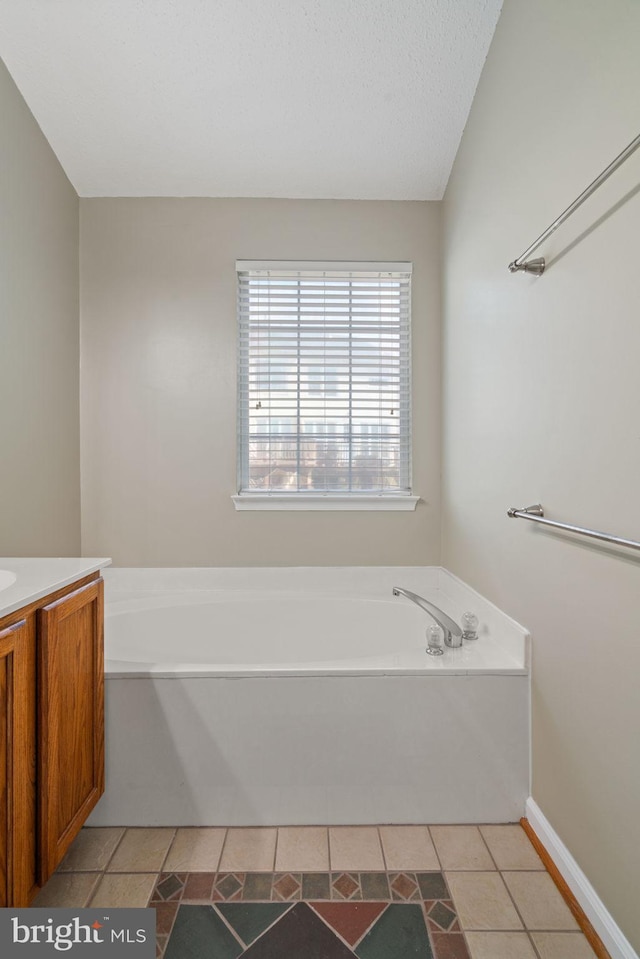 full bath with a garden tub, baseboards, and vanity