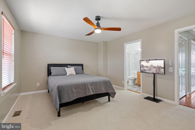 bedroom featuring ceiling fan, light colored carpet, baseboards, ensuite bathroom, and visible vents