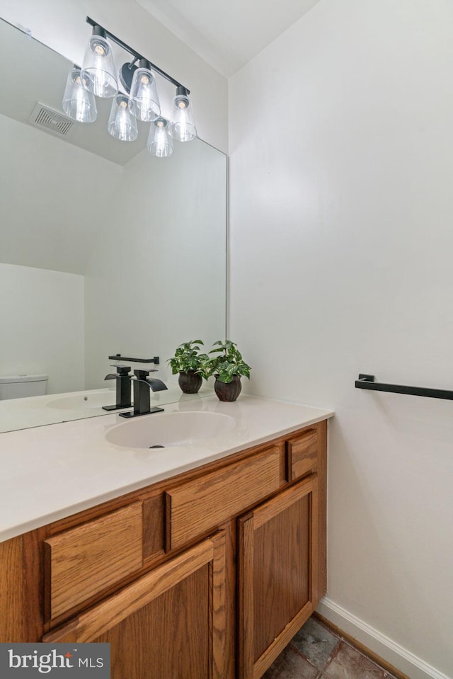 bathroom with vanity, baseboards, toilet, and visible vents