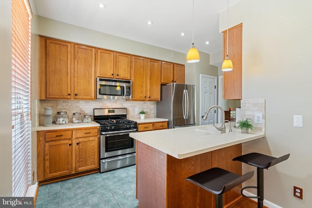 kitchen with appliances with stainless steel finishes, a breakfast bar, brown cabinetry, a peninsula, and decorative backsplash