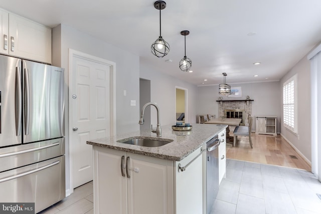4011 Hummer Rd, Annandale, VA 22003 - kitchen with appliances with stainless steel finishes, a sink, white cabinets, a brick fireplace, and open floor plan
