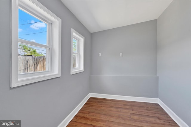 spare room featuring baseboards and wood finished floors