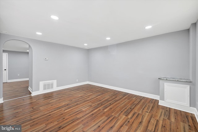 below grade area with visible vents, arched walkways, wood finished floors, baseboards, and recessed lighting