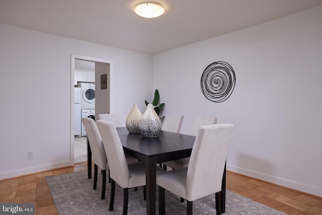 dining space featuring stacked washer / drying machine, baseboards, and electric panel