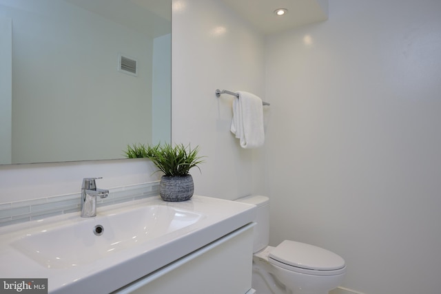 half bath featuring toilet, visible vents, and vanity