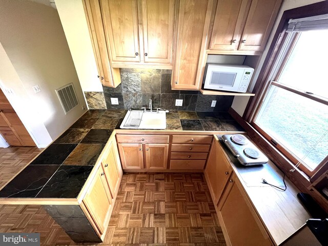 3903 8th St S, Arlington, VA 22204 - kitchen with a sink, white microwave, tile countertops, a peninsula, and tasteful backsplash