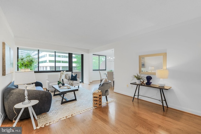 living room featuring crown molding, wood finished floors, baseboards, and a chandelier