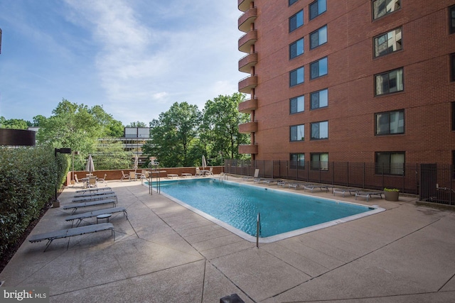 community pool with fence and a patio