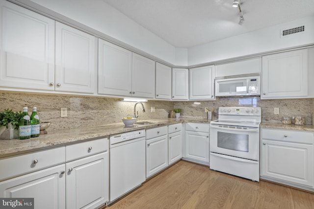 kitchen with white appliances, a sink, white cabinetry, and light wood-style floors