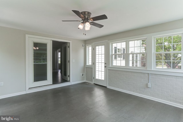 unfurnished room featuring baseboards, a ceiling fan, dark wood-type flooring, and a healthy amount of sunlight