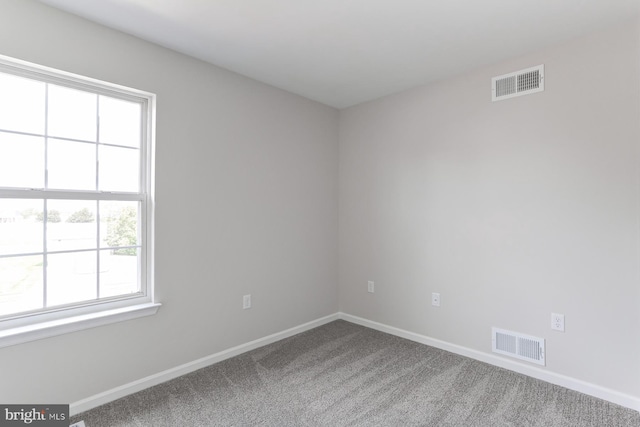 carpeted spare room featuring visible vents and baseboards