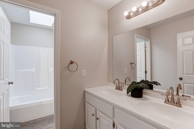 bathroom featuring a sink, a skylight, double vanity, and shower / washtub combination