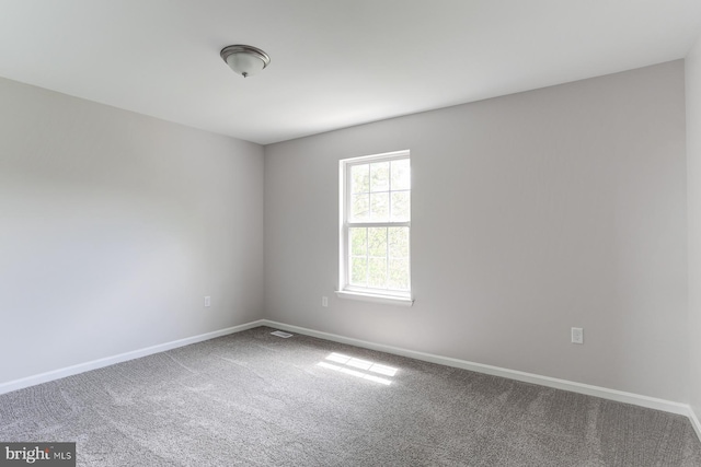 carpeted empty room featuring baseboards and visible vents