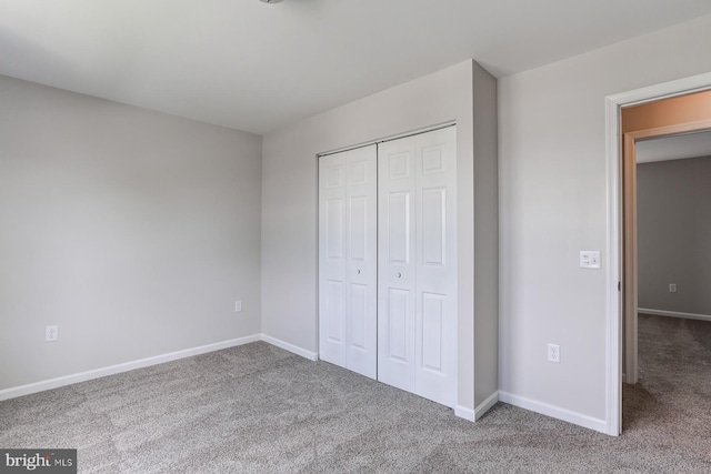 unfurnished bedroom featuring carpet flooring, baseboards, and a closet
