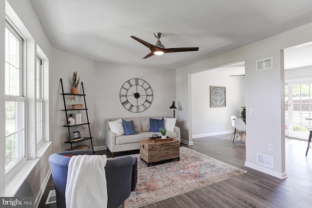 living area featuring visible vents, a ceiling fan, baseboards, and dark wood-style floors