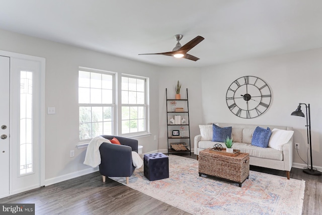 living room featuring baseboards, ceiling fan, and wood finished floors