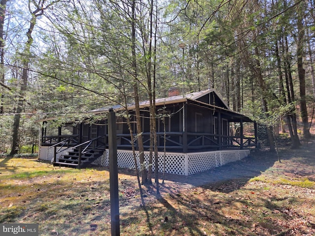 back of house featuring board and batten siding and a view of trees