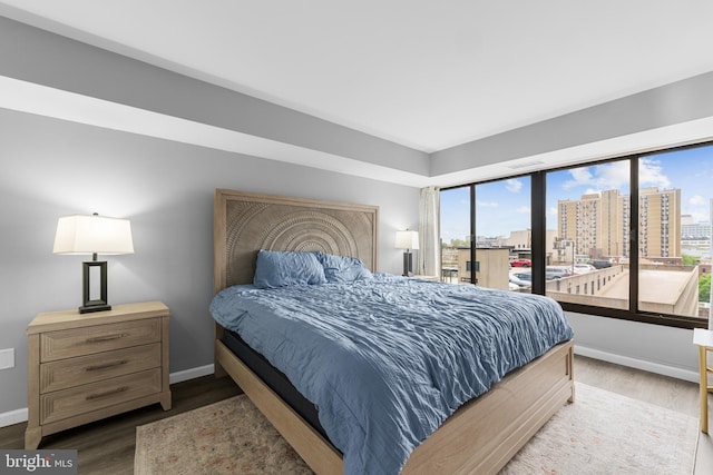 bedroom featuring baseboards, multiple windows, and wood finished floors
