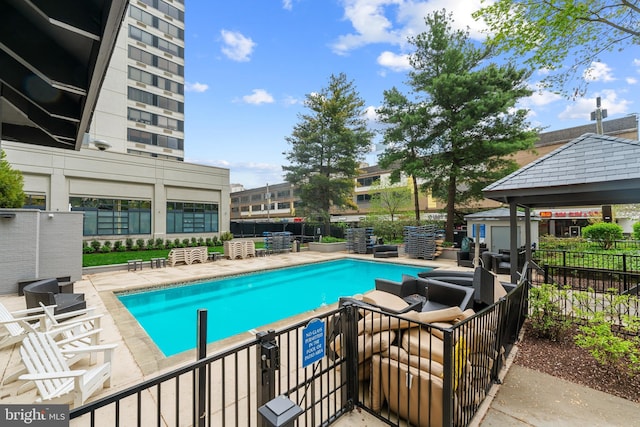 community pool with a storage shed, a patio, fence, and an outdoor structure