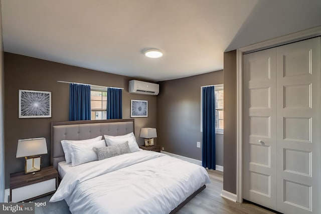 bedroom featuring baseboards, wood finished floors, a wall mounted AC, and a closet