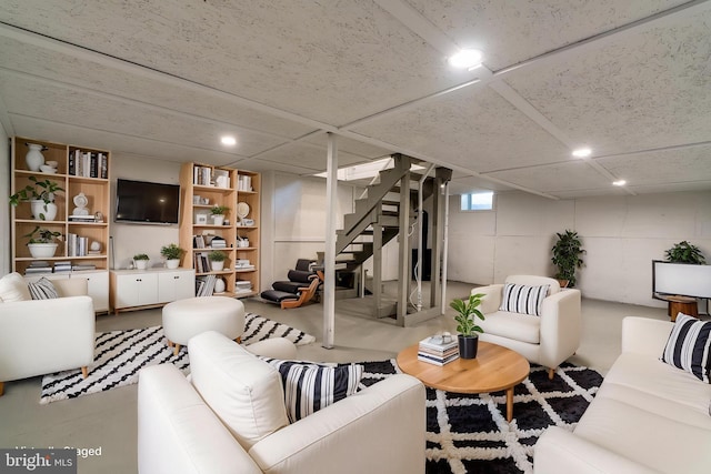 living area featuring concrete flooring, recessed lighting, and stairs