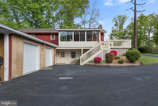 711 Clymer Ave, Sellersville, PA 18960 - view of front of house featuring asphalt driveway, a garage, a sunroom, a chimney, and stairway