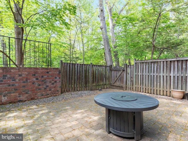 view of patio featuring a fenced backyard, a gate, and a fire pit