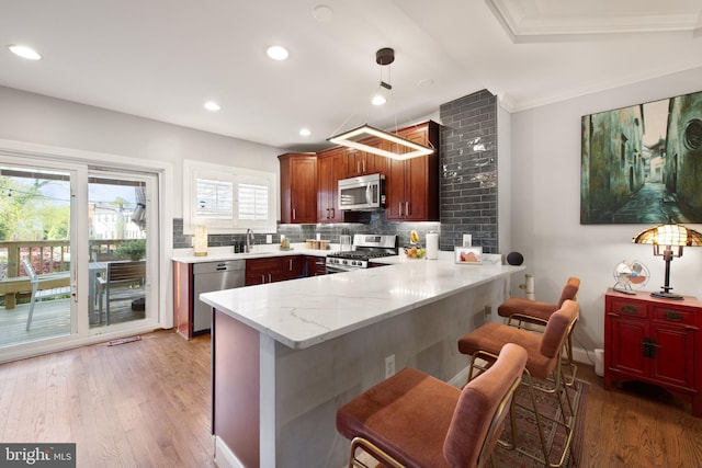 728 Farragut St NW, Washington, DC 20011 - kitchen with appliances with stainless steel finishes, a sink, light wood finished floors, a peninsula, and decorative backsplash
